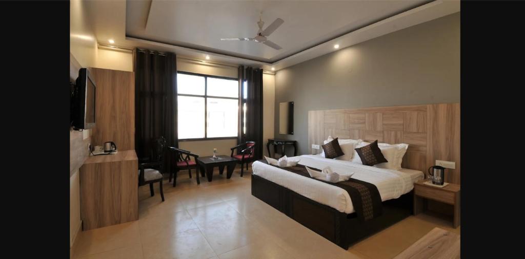Una habitación de hotel con una cama y un comedor. en Hind Hotel Near Airport Road Mohali Zirakpur, en Zirakpur