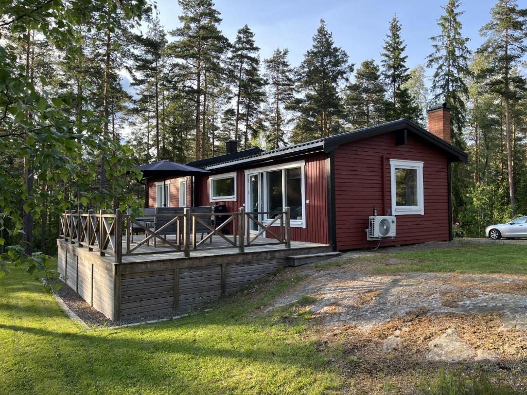 una piccola cabina rossa con un grande ponte di Charming cottage with partial lake view near Hultsfred a Bjärkhult