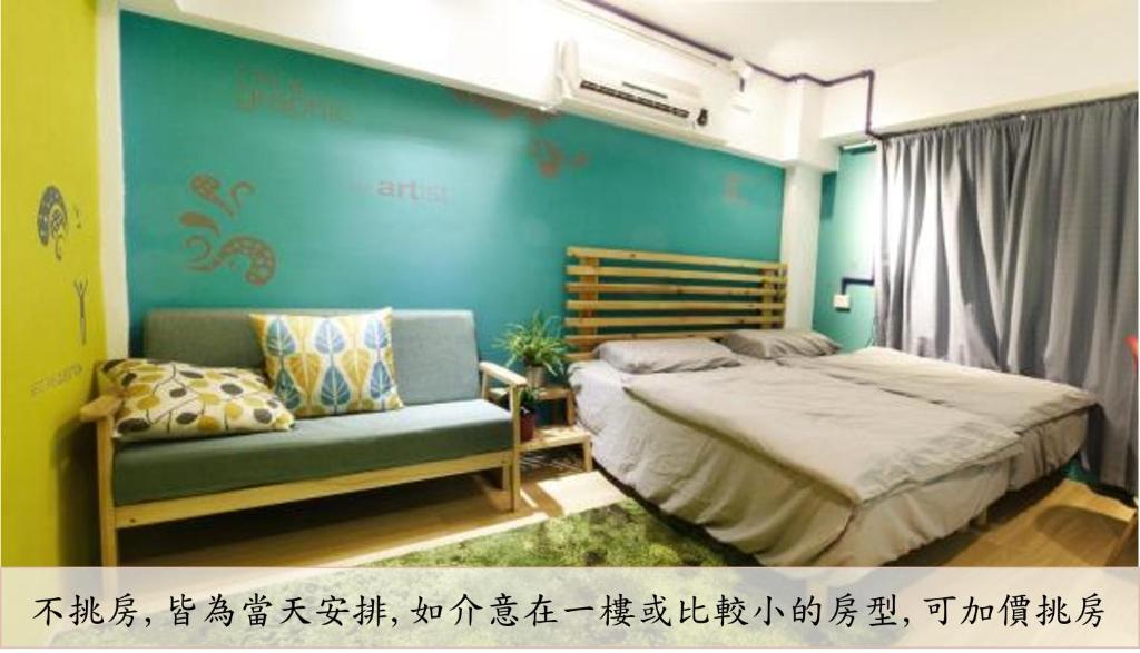 a bedroom with a bed and a couch and a blue wall at Leo Ho Hostel in Tainan