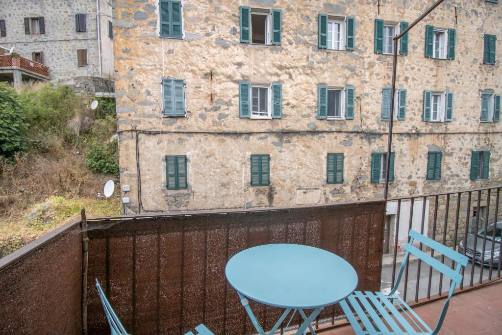 a blue chair on a balcony with a building at La maison de Mina in Olmeto