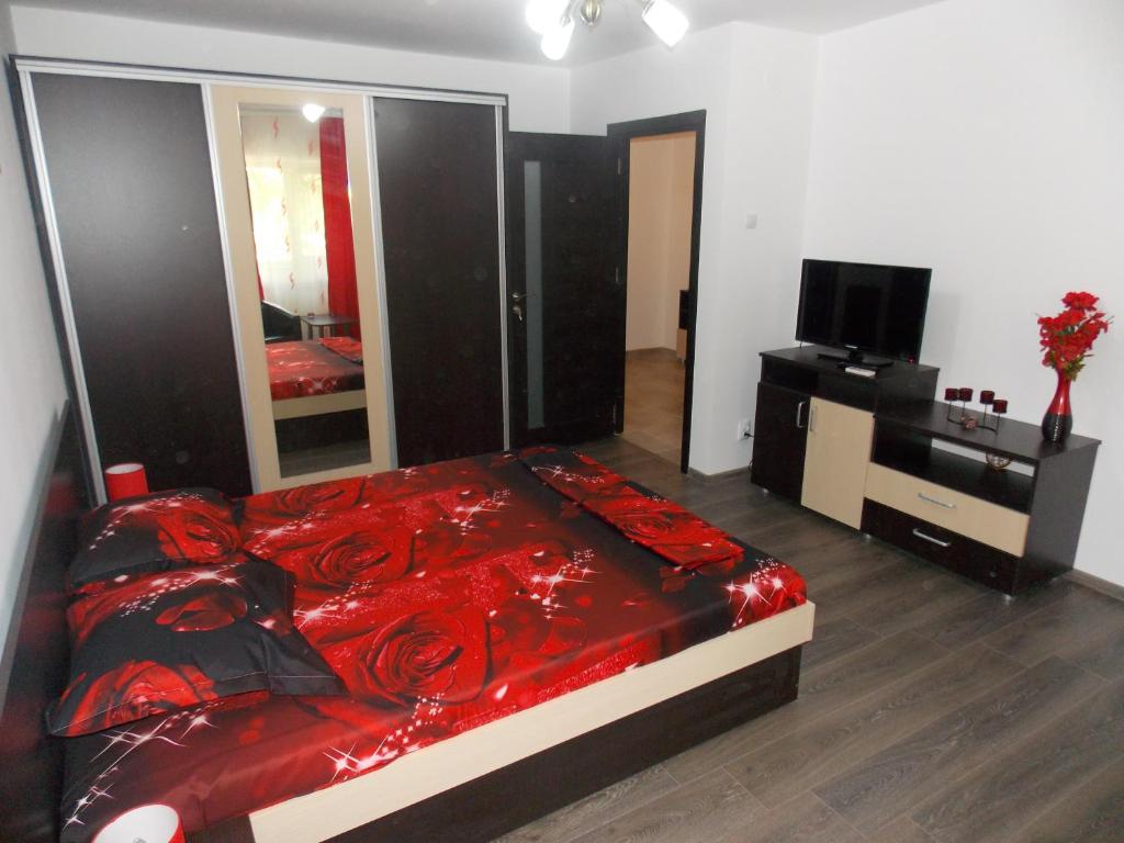 Cette chambre comprend un lit avec des draps rouges et une télévision. dans l'établissement Studio Lujerului 2, à Bucarest