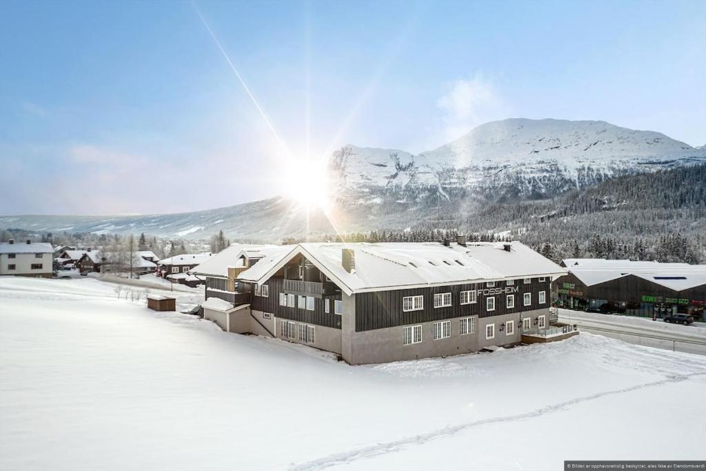 a house in the snow with a mountain in the background at Charming apartment with lodgefeeling in Hemsedal