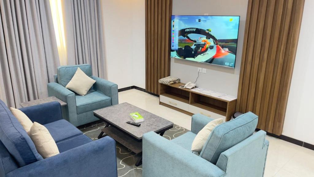 a living room with two blue chairs and a tv at بيت خزامى للشقق الفندقية المخدومة in Najran