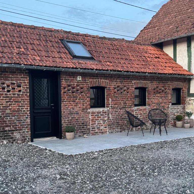 a brick house with a black door and two chairs at A la ferme - Colline Beaumont in Colline-Beaumont