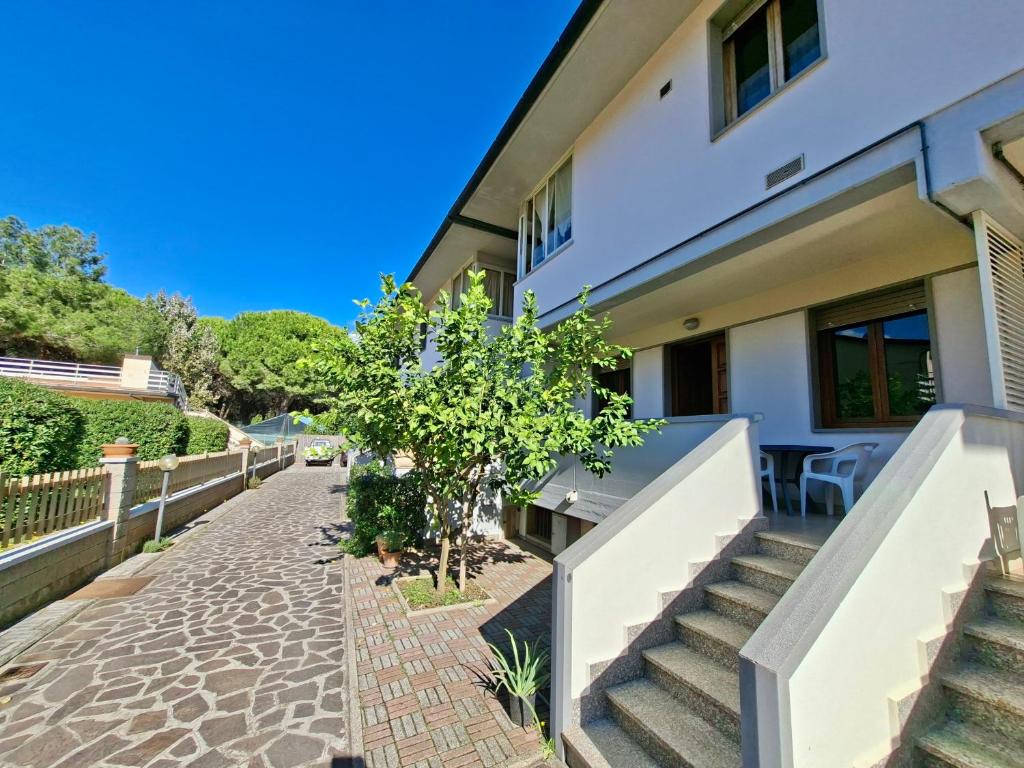 a house with stairs and a tree in front of it at ISA - Felci 19, apartment 6 beds in Marina di Bibbona just 300 mt from the sea in Marina di Bibbona