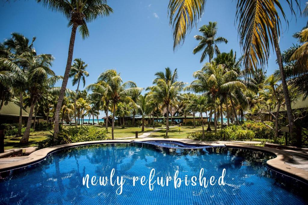 a swimming pool with palm trees in the background at Paradise Sun Hotel Seychelles in Baie Sainte Anne