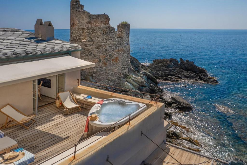a bath tub sitting on a deck next to the ocean at Maison de pêcheur dans le Cap Corse in Erbalunga