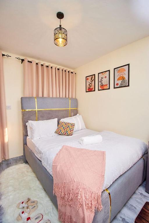 a bedroom with a bed with a pink blanket on it at Happy Homes Airbnbs- Kikuyu in Nairobi