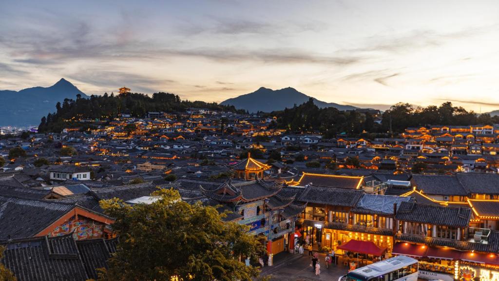 a view of a city at night with mountains at Sujianbeicheng Guanjing Meisu Inn in Lijiang