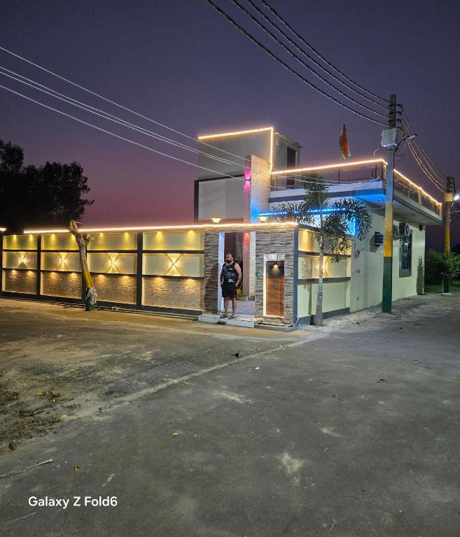 a person standing outside of a gas station at night at Shera farm in Khatauli