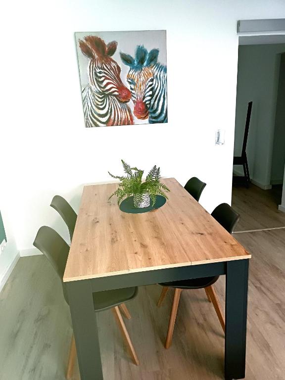 a wooden table with chairs and a painting of zebras at Apartment Henry I in Schiffweiler
