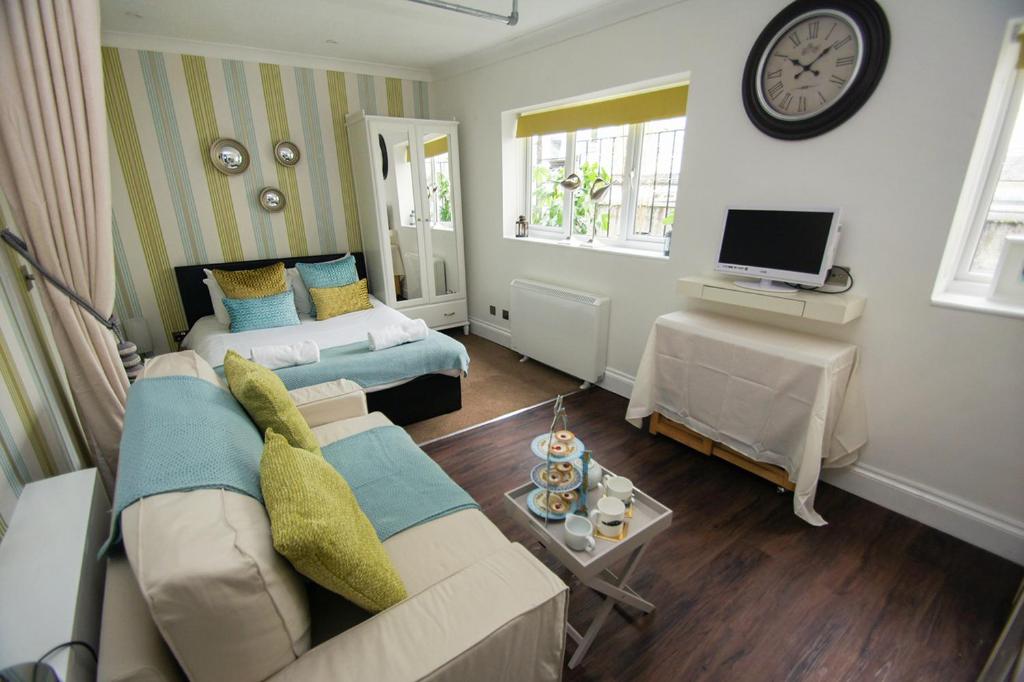 ein Wohnzimmer mit einem Sofa, einem Bett und einer Uhr in der Unterkunft Between Piers - Central- by Brighton Holiday Lets in Brighton & Hove