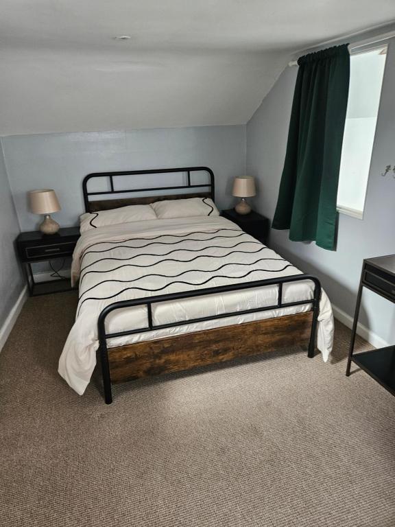 1 cama en un dormitorio con 2 lámparas en las mesas en The coach house, en Nottingham