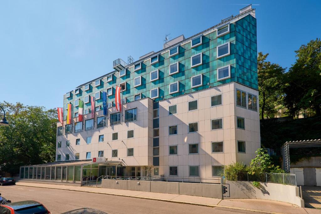 a tall building with flags on top of it at Hotel Strudlhof Vienna in Vienna