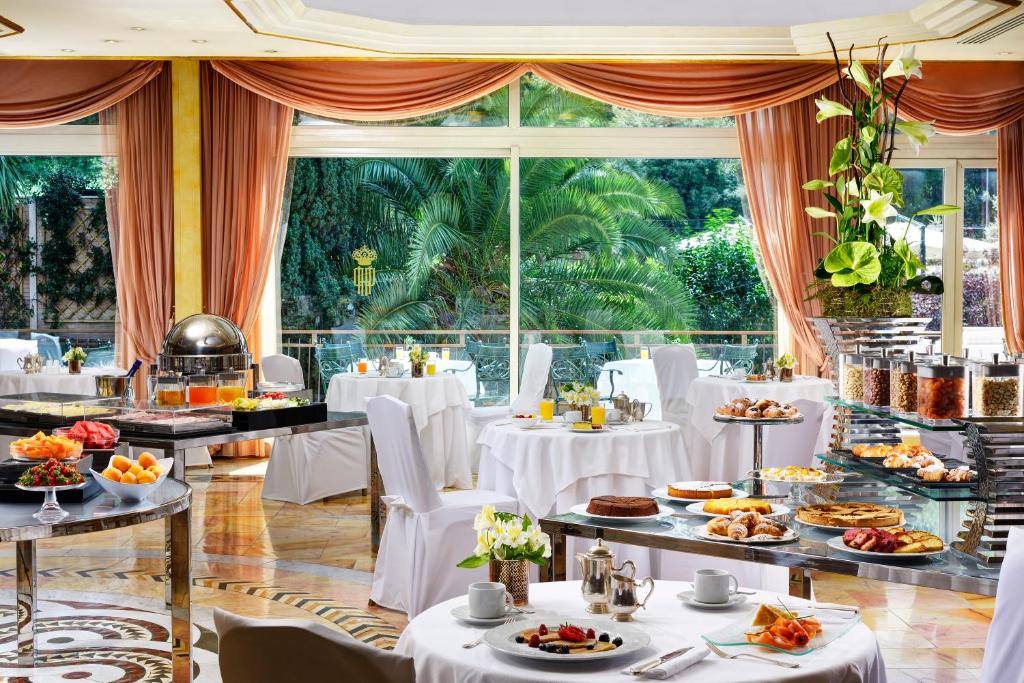 Un restaurante con mesas y sillas blancas y un gran ventanal. en Parco dei Principi Grand Hotel & SPA, en Roma