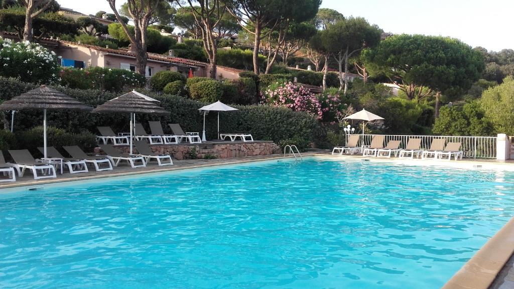 une grande piscine bleue avec des chaises et des parasols dans l'établissement Appartement Marina di santa giulia, à Porto-Vecchio
