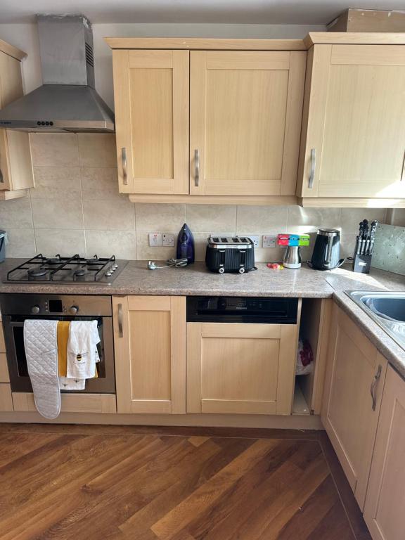 a kitchen with wooden cabinets and a stove top oven at Modern 3-Bedroom Home 3 Minutes from Biggin Hill Airport - Secure Gated Community in Biggin Hill