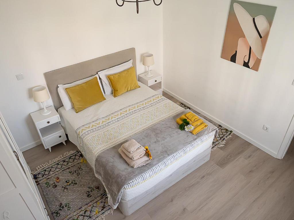 a bedroom with a bed with yellow pillows and two tables at Casa do João e da Teresa in Ribeira Brava