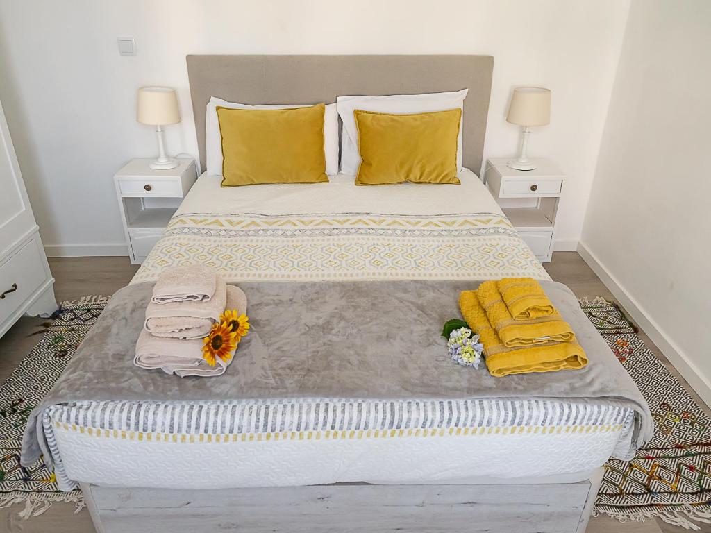 a large bed with yellow pillows and towels on it at Traditional Madeira House Garden, Terrace & BBQ in Ribeira Brava