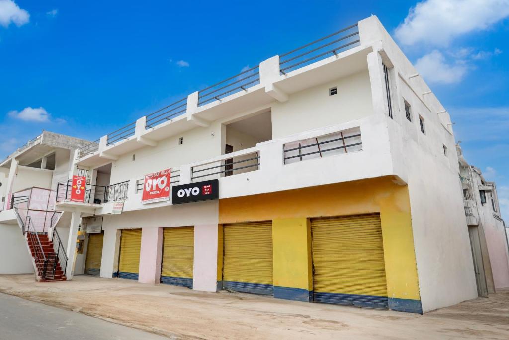 um prédio branco com portas amarelas e uma cesta de basquete em Hotel O Sky Villa em Nagpur