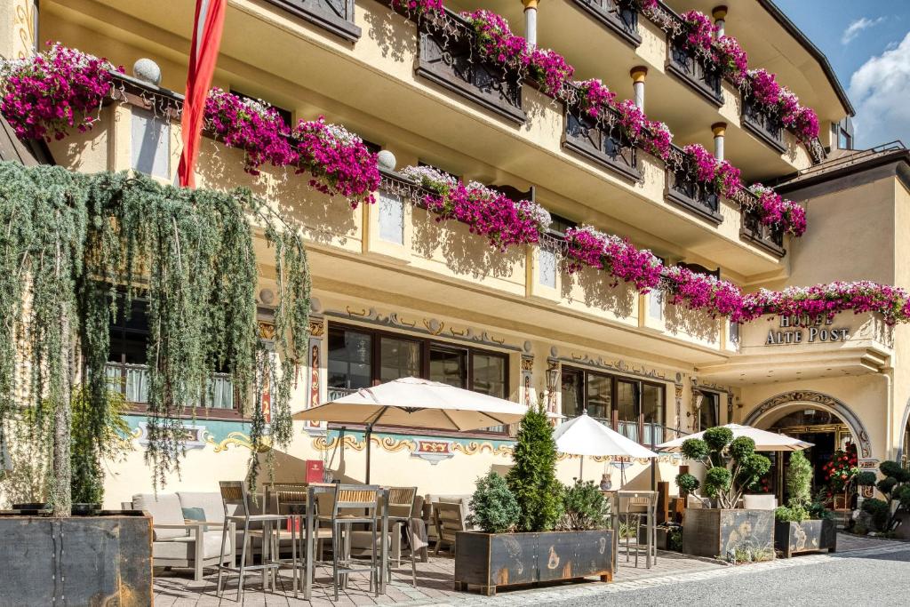 a building with tables and chairs and flowers on it at Hotel Alte Post in Sankt Anton am Arlberg