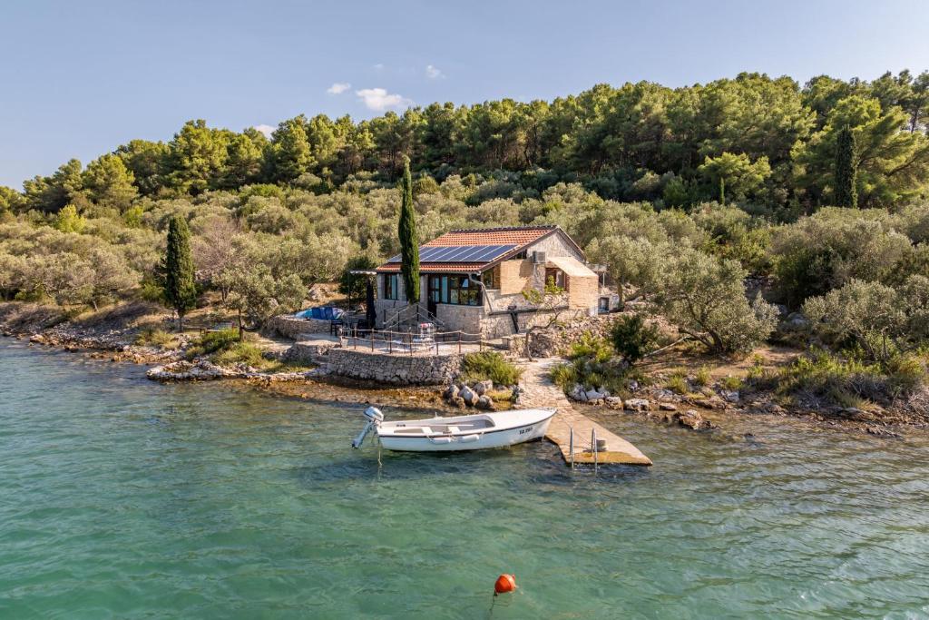 a house with a boat on a dock in the water at Villa Zora ZadarVillas - private island retreat in Sali