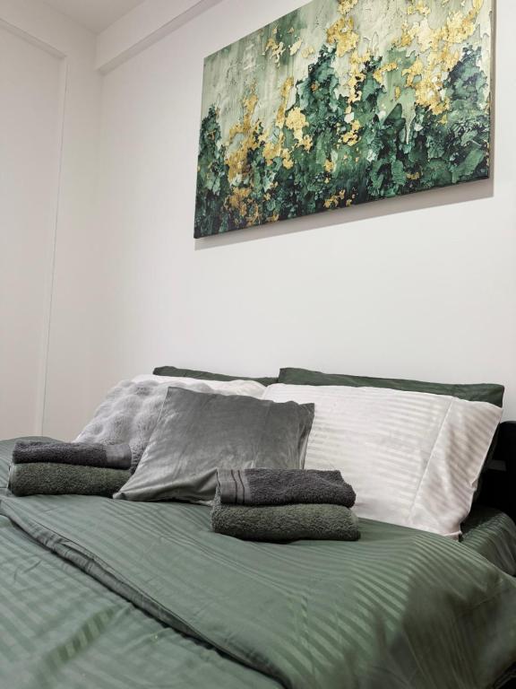a bed with two pillows and a painting on the wall at Apartman Lambros in Soko Banja