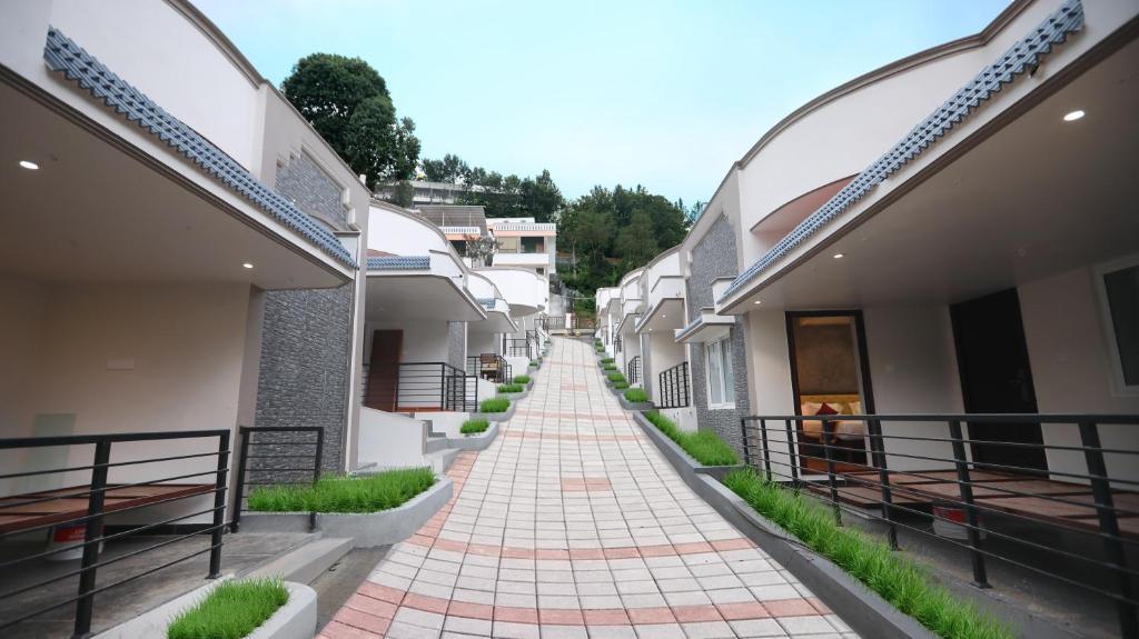 a walkway between two buildings with grass at WOW Naturefull Resorts in Yercaud
