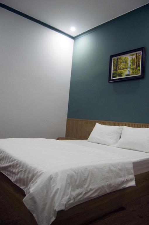a bedroom with a white bed with a picture on the wall at Hotel88 in Ấp Bình Hưng