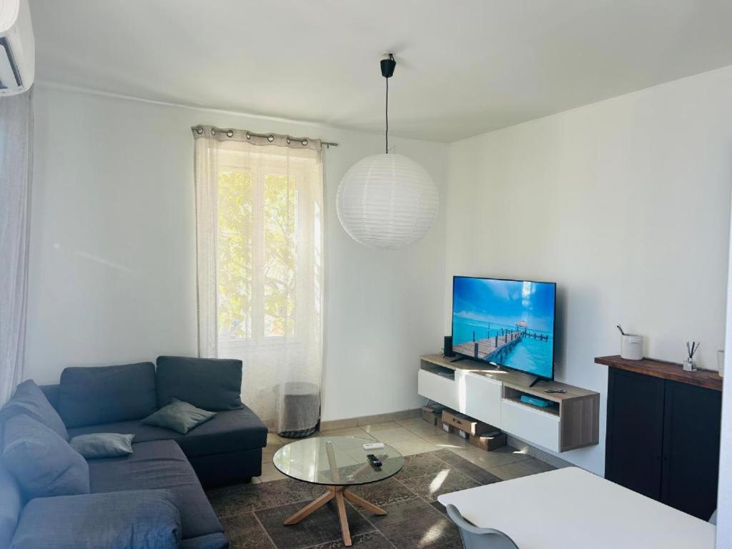 Una sala de estar con un sofá azul y un televisor. en Chambre d hotes Marseille Prado, en Marsella