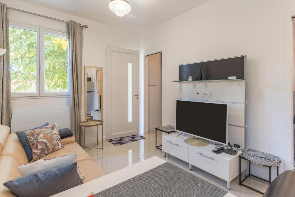 Una sala de estar con un sofá y un televisor de pantalla plana. en Appartement indépendant avec jardin, en Pont de lʼArc