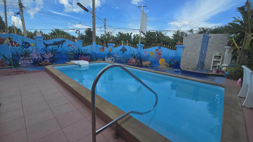 une grande piscine avec une fresque murale dans l'établissement Araya's House, à Hua Hin