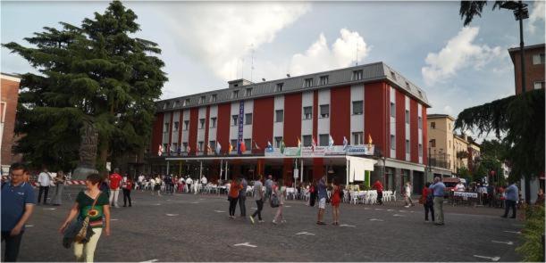 grupa ludzi stojących przed czerwonym budynkiem w obiekcie Hotel Domus w mieście Maranello
