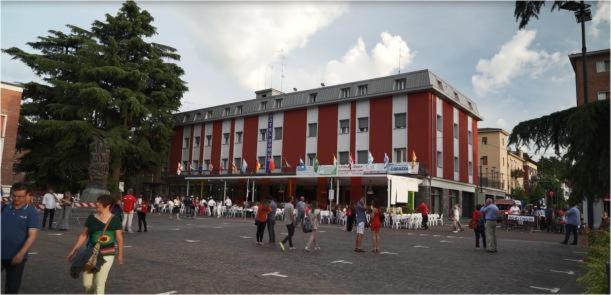 un grupo de personas de pie en frente de un edificio rojo en Hotel Domus, en Maranello