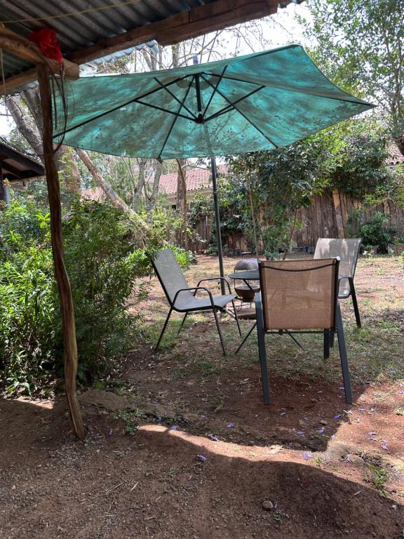 una mesa y dos sillas bajo una sombrilla en Karen Cottage with Private Garden WiFi, en Nairobi