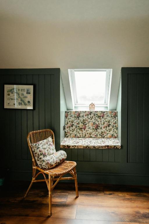 a chair in a room with a window and a bench at Louisa's Loft in Killyhevlin