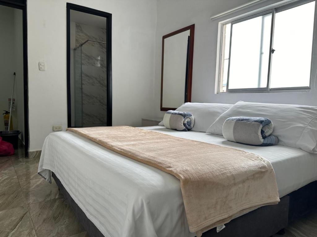 a bedroom with two beds with white sheets and a window at Hotel Cadiz Boutique in Santa Rosa de Cabal