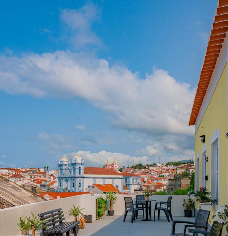 a balcony with chairs and tables overlooking a city at Yellow House - Casa 2 in Angra do Heroísmo