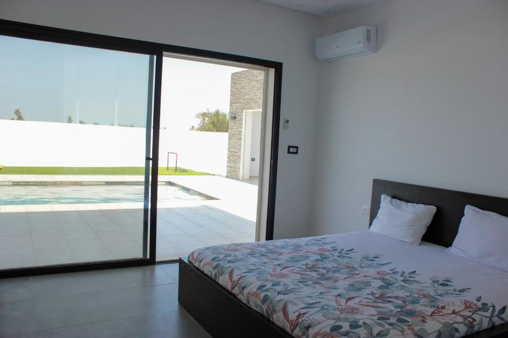 une chambre avec un lit et une porte coulissante en verre dans l'établissement Villa Les Palmiers, à Temlale