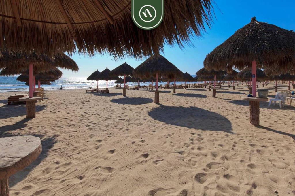 - une plage de sable avec des parasols en paille et l'océan dans l'établissement Amazing Studio with Terrace Overlooking the Ocean, à Nuevo Nayarit