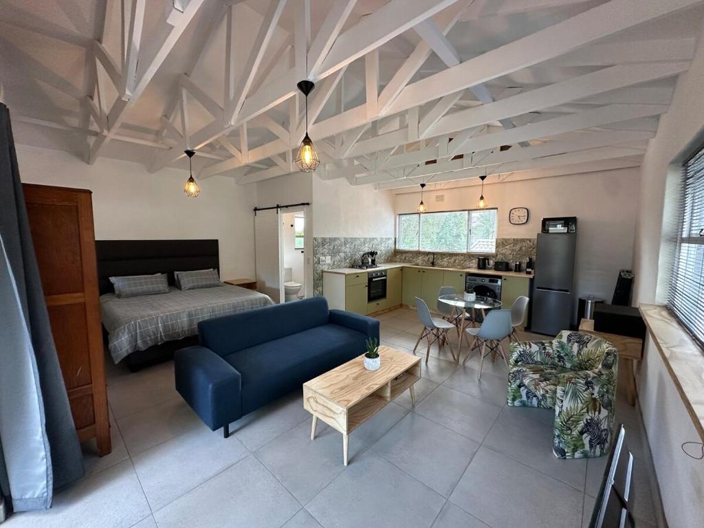 a living room with a blue couch and a bed at Studio 33 Pendeen in Plettenberg Bay
