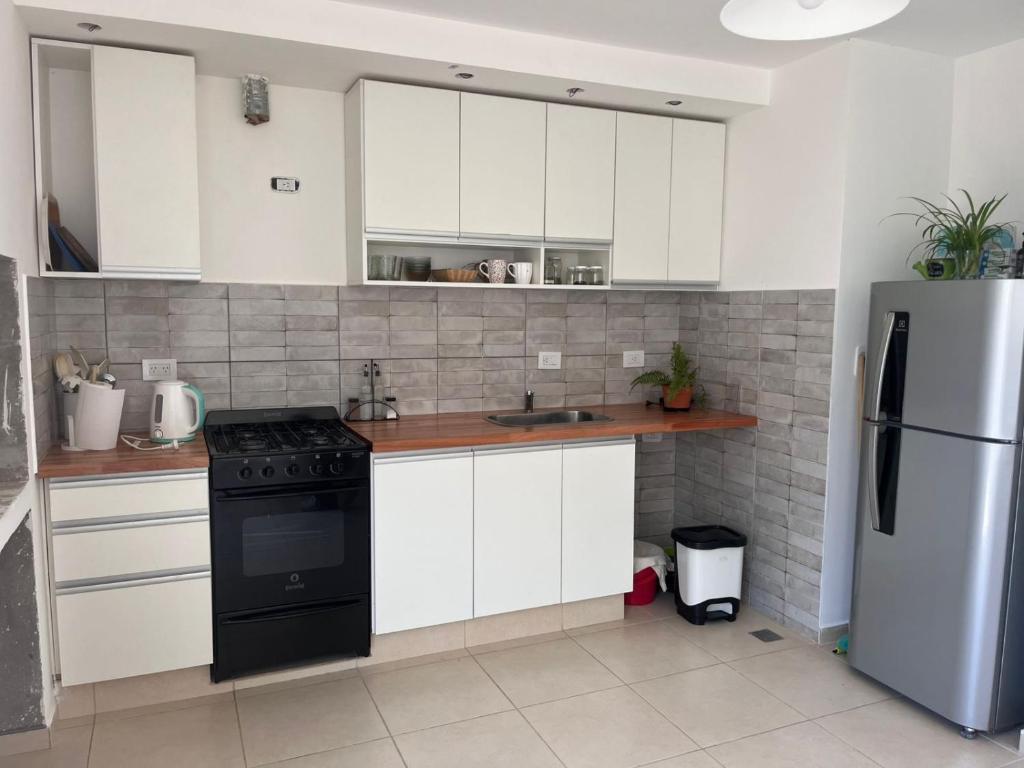 a kitchen with white cabinets and a black refrigerator at Santa Lucía in Playa Unión
