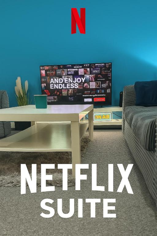 Una sala de estar con una mesa y un televisor. en The Netflix Suite, en Leicester