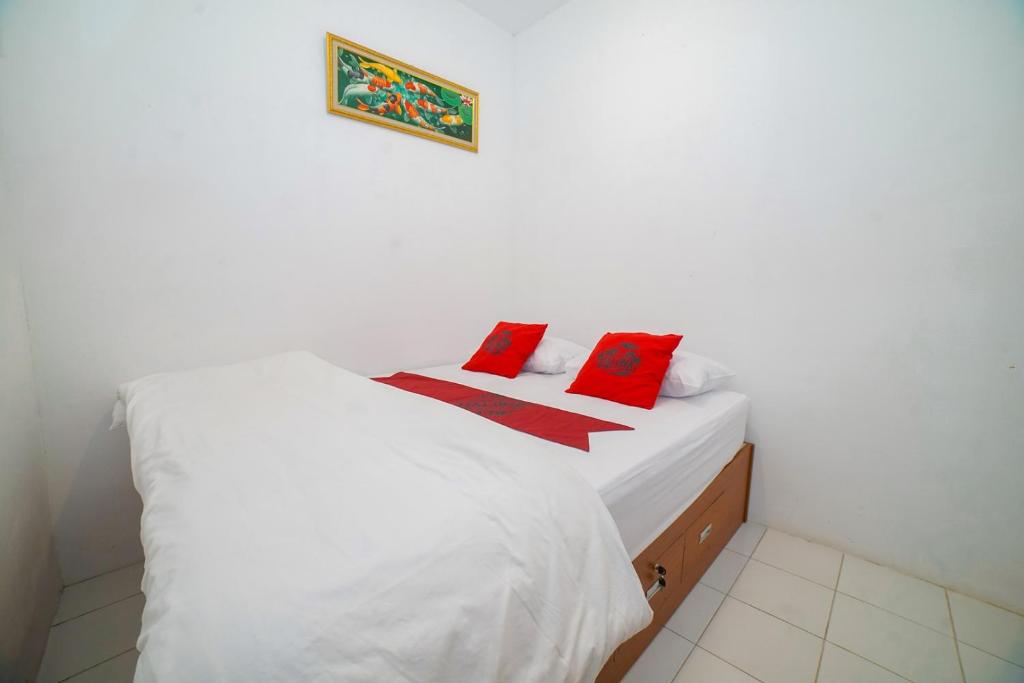 une chambre avec un lit blanc avec des oreillers rouges dans l'établissement Halona Taraman Guest House by Yurooms, à Ngemplak