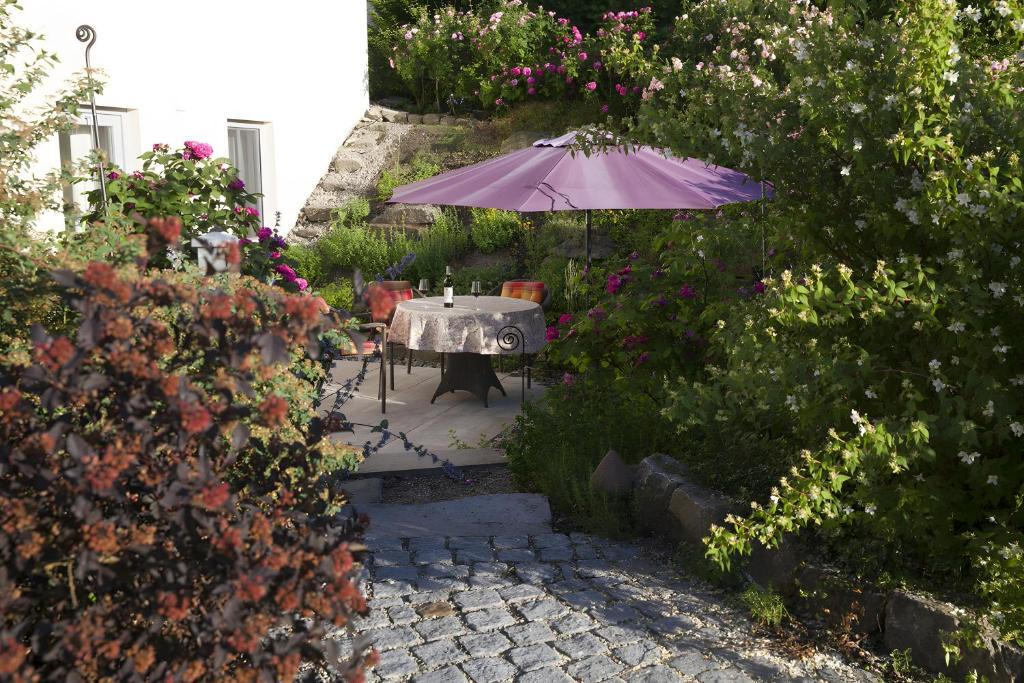 a table with an umbrella in a garden with flowers at Ferienwohnung Im Schiller in Wiesenbronn