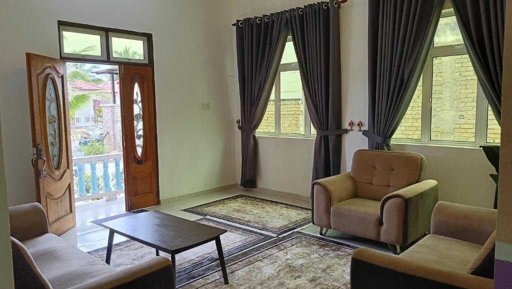 a living room with chairs and a table and windows at Homestay Annur Barakah in Kampung Raja