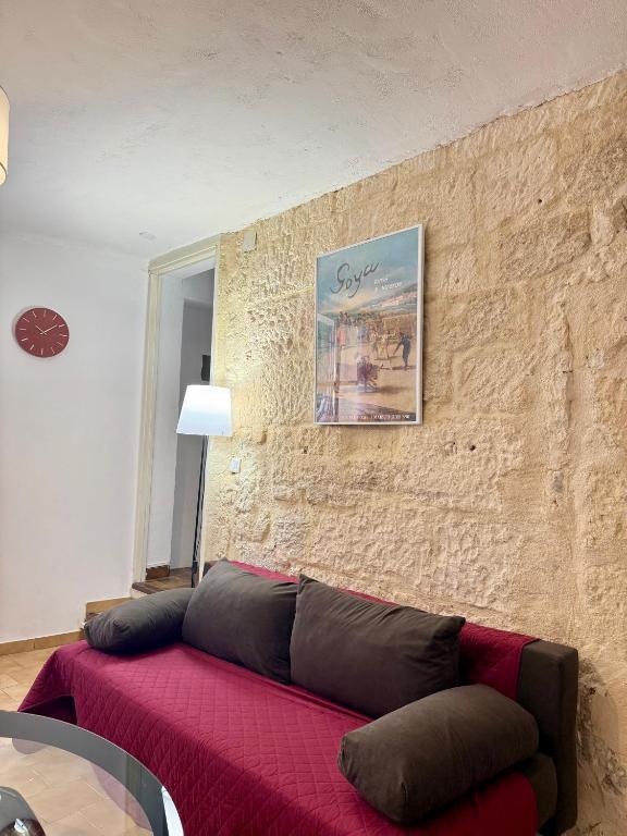 a living room with a red couch against a brick wall at Le Cocon D'Alembert in Arles