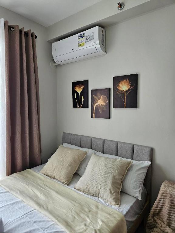 SubaCozy Studio with Balcony and Pool Near Airport and Beaches的卧室内的一张床铺,墙上有三幅画