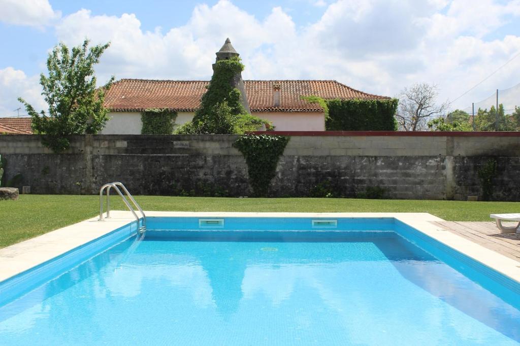 a swimming pool in a yard next to a wall at Casa do Caseiro, São Silvestre in São Silvestre