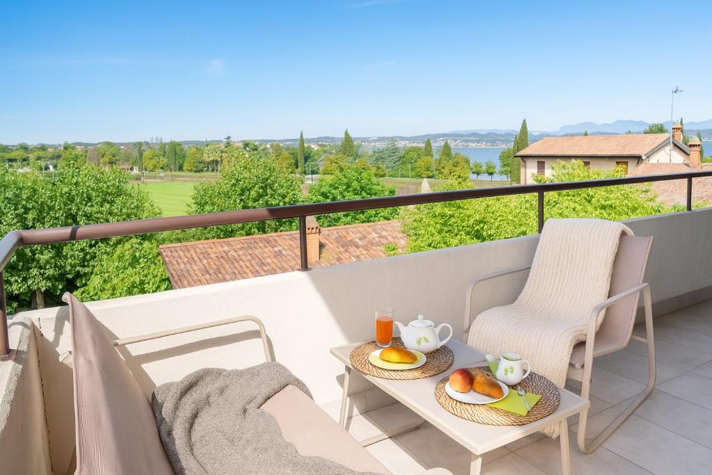 a balcony with two chairs and a table with food on it at Neela Apartment Romantic Lake View with Balcony & Parking in Desenzano del Garda